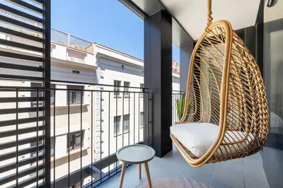 a swinging chair on a balcony with a view of a building at CATERINA Gràcia in Barcelona