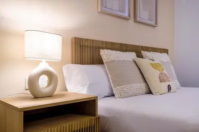 a bed with white pillows and a lamp on a night stand at CATERINA Gràcia in Barcelona