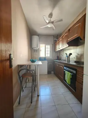 a kitchen with wooden cabinets and a ceiling fan at Apartamento en la playa in Cunit