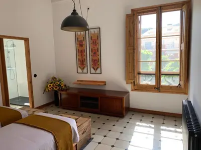 a bedroom with a bed and a table and a window at Ca l'Andreu Teià. Casa modernista in Teià