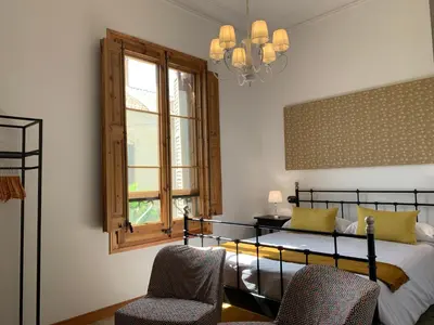 a bedroom with a bed and two chairs and a window at Ca l'Andreu Teià. Casa modernista in Teià