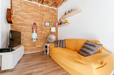 a living room with a couch and a brick wall at Beachside Bliss Charming 1-bedroom, Barceloneta in Barcelona