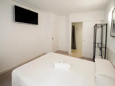 a white bed in a room with a tv on the wall at L'Hostalet GuestHouse in Pineda de Mar