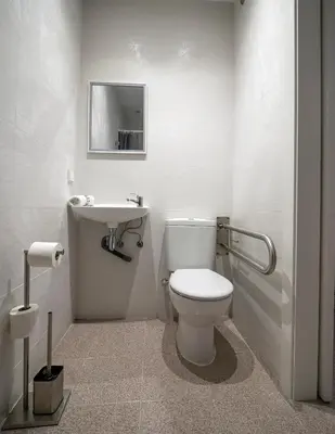a white bathroom with a toilet and a sink at L'Hostalet GuestHouse in Pineda de Mar