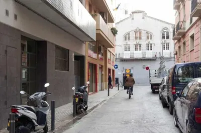 a person riding a bike down a street with parked cars at Port VII Apt centrico acogedor w balcon 23 in Barcelona