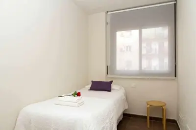 a small bedroom with a white bed with a window at Port III Apart céntrico ideal familias 11 in Barcelona