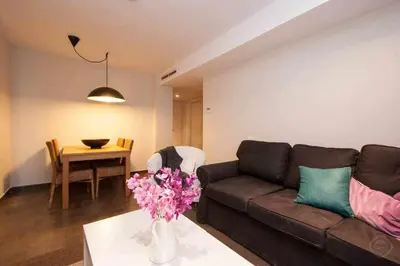 a living room with a couch and a table with flowers at Port IV Apart céntrico ideal grupos 12 in Barcelona