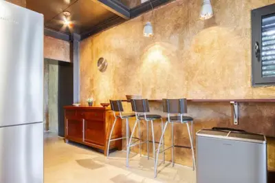 a kitchen with a bar with stools and a refrigerator at Masia Cal Sisplau, con piscina y rodeada de viñedos a 10 minutos de Vilafranca del Penedés, Barcelona ,Cataluña in San Martín Sarroca