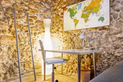 a desk and chair in a room with a stone wall at Masia Cal Sisplau, con piscina y rodeada de viñedos a 10 minutos de Vilafranca del Penedés, Barcelona ,Cataluña in San Martín Sarroca