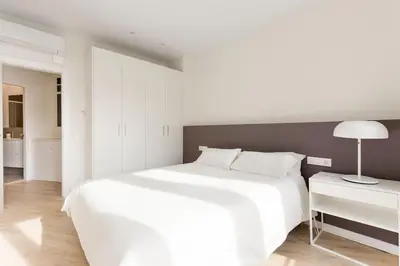 a white bedroom with a large white bed and a lamp at Modern and bright apartment well located in Gracia in Barcelona
