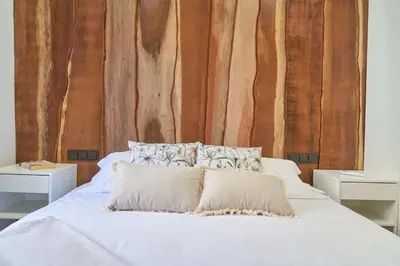 a bed with white sheets and pillows in front of a wooden wall at Stay U-nique Apartment Padilla in Barcelona