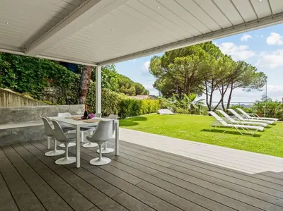 a patio with a table and chairs on a deck at Design villa sea views and lap pool in Cabrils