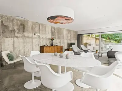 a dining room with a white table and white chairs at Design villa sea views and lap pool in Cabrils