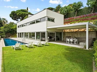 a large white house with a pool and lawn at Design villa sea views and lap pool in Cabrils