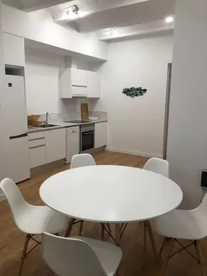 a kitchen with a white table and white chairs at Gaudi Street Apartments in Sitges
