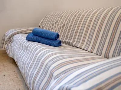 two blue towels sitting on a striped couch at Apartment Els Pins by Interhome in Sant Vicenç de Montalt