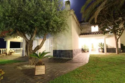 a house with a tree and a sign in the yard at Basketball court, pool, BBQ, gardens, seaviews in San Pol de Mar