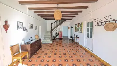 a room with a hallway with a staircase and a table and chairs at Historic house 5 minutes walk from the beach in San Pol de Mar