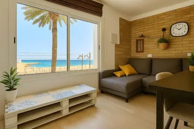 a living room with a couch and a palm tree at La Bellamar - Apartamento en primera línea mar- in Premiá de Mar