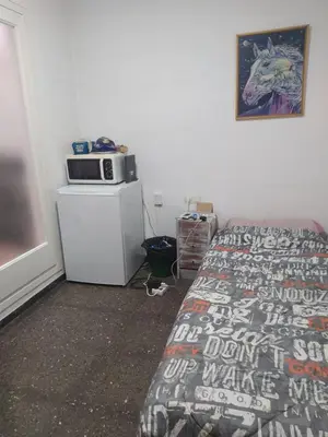 a room with two beds and a microwave on a refrigerator at Primera línea de mar y piscina a 20 minutos de Barcelona in Premiá de Mar