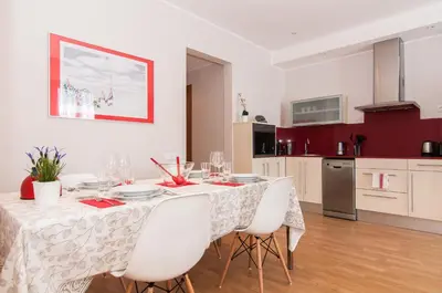 a dining room table with white chairs and a kitchen at Pelayo Deluxe Apartments in Barcelona