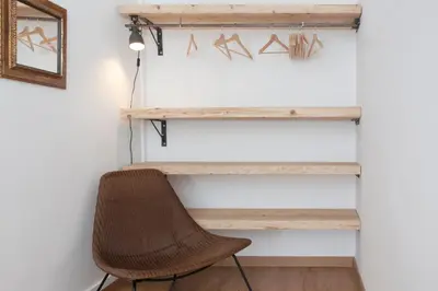 a desk with a rattan chair in front of a wall at My Address in Sant Antoni in Barcelona