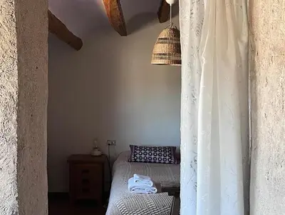 a bedroom with a bed with a white curtain at Cal Muntanyès in Font-Rubí