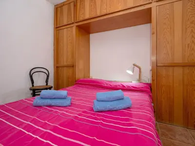 a bedroom with a pink bed with two blue pillows on it at Apartment Zodiak by Interhome in Pineda de Mar
