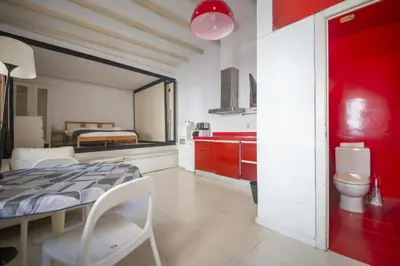 a room with a bed and a kitchen with red cabinets at Catalunya Casas Pied-à-terre in central Barcelona 100m from beach in Barcelona