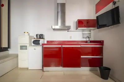a small kitchen with red cabinets and a microwave at Catalunya Casas Pied-à-terre in central Barcelona 100m from beach in Barcelona