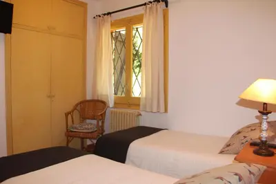a bedroom with two beds and a window and a chair at Hostal l´Ou de Reig in Montseny