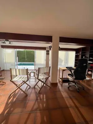 a living room with chairs and a table and a desk at Casa familiar en la playa con piscina in Teià