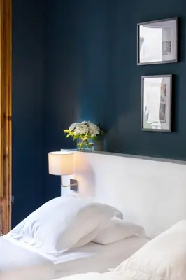 a bedroom with a blue wall with a bed and a vase with flowers at Hostal Sol y K in Barcelona