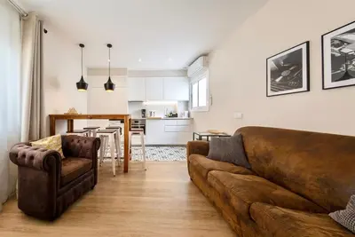 a living room with a brown couch and a kitchen at MadreMia - Chic Hub Barcelona in Hospitalet de Llobregat