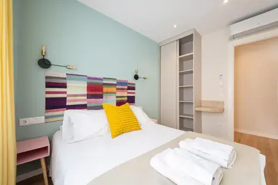 a bedroom with a white bed with a yellow pillow at MadreMia - Chic Hub Barcelona in Hospitalet de Llobregat