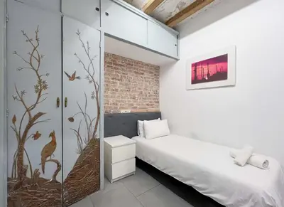 a small bedroom with a bed and a brick wall at Stay U-nique Apartment Comte Urgell II in Barcelona