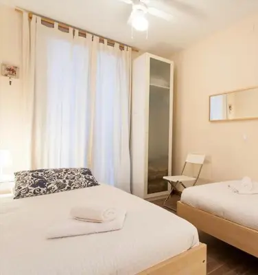 a bedroom with two beds and a window with a chair at Apartament modern al carrer Blai, Poble Sec in Barcelona