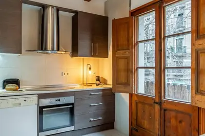 a kitchen with wooden cabinets and a window at Canela Homes BARCELONA SANT ANTONI in Barcelona