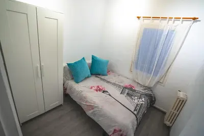a small bedroom with a bed with blue and pink pillows at Flat Top Manager in Barcelona