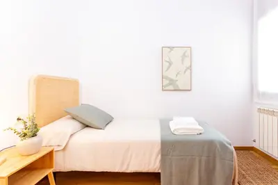 a white bedroom with a bed and a table at Elegante dúplex en Terrassa, Barcelona in Terrassa