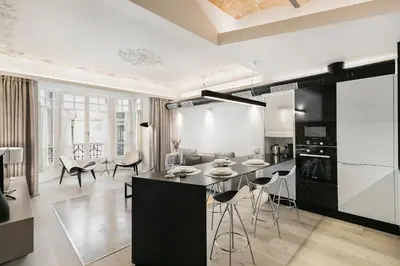 a kitchen with a black island and stools at BCN Town Apartments Portaferrissa in Barcelona