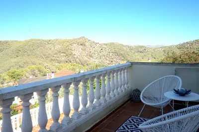 a balcony with a table and chairs and mountains at Habitación Atalaya in Olivella