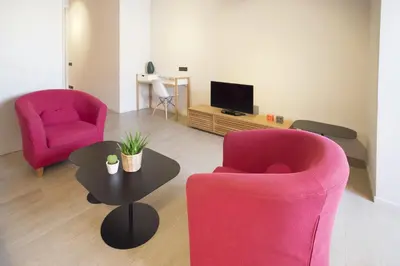 a living room with two pink chairs and a table at Barcelona InLoft in Barcelona