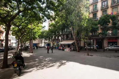 a street with trees and a scooter parked on a sidewalk at Rustic Poble Sec Apartment in Barcelona