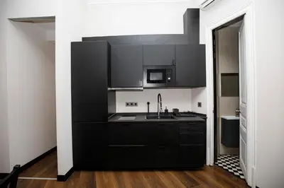 a black kitchen with a sink and a microwave at Classic styled apartment in Barcelona