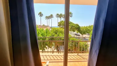a window with a view of a balcony with palm trees at Apartamento Cabrera Burriac in Cabrera de Mar