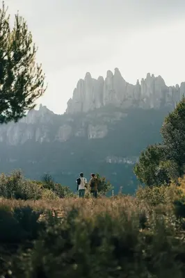 three people standing on a hill with a mountain in the background at Apartament Roca Foradada in Monistrol
