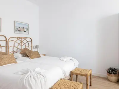 a white bedroom with a bed and a table at Matarolux24 in Mataró