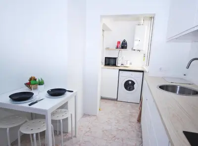 a small white kitchen with a sink and a table at Can Josep in Vilassar de Mar