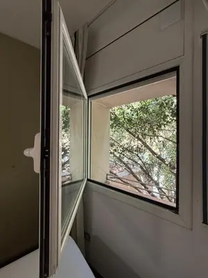 a window in a bedroom with a tree outside at Maravilloso piso en el corazón de Barcelona in Barcelona